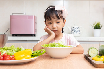 Asian Chinese little girl eating salad in the kitchen - obrazy, fototapety, plakaty