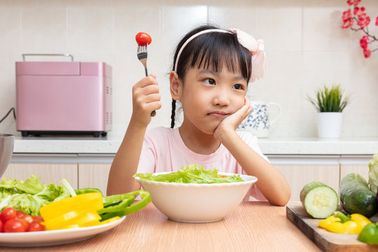 Asian Chinese Little Girl Eating Salad In The Kitchen