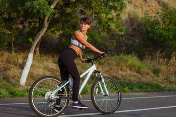 Obraz premium Pretty girl on bike in the Park, in the rays of the Sun Sunrise 