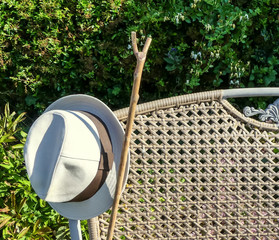 Partial view of an old woven backed garden bench, with old brimmed hat and walking stick. Early...