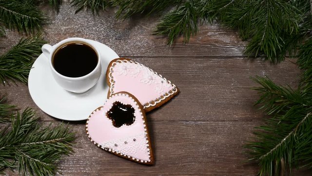 Food art. Good morning concept. Fir tree as a frame, cup of coffee and 2 heart-shaped gingersnaps are on wooden background.
