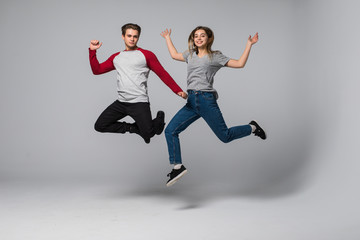 Fototapeta na wymiar Beautiful smiling young couple jumping isolated on white background