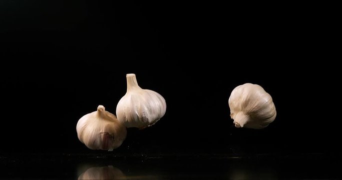 Garlic, allium savitum, falling against Black Background, Slow Motion 4K
