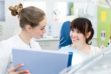 Dentist in a white coat shows the results of the survey to the client