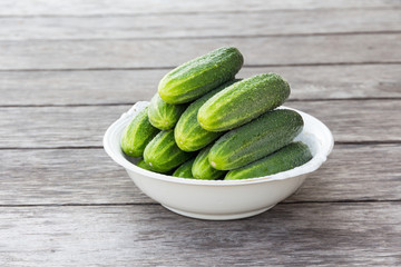 whole green cucumbers in a large white antique plate on a wooden table