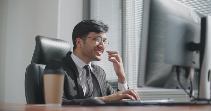 young iranian businessman working at computer in office, then celebtating successful business deal. business, victory concept 4k