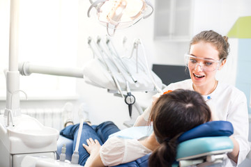 Obraz premium Beautiful girl dentist examines the oral cavity