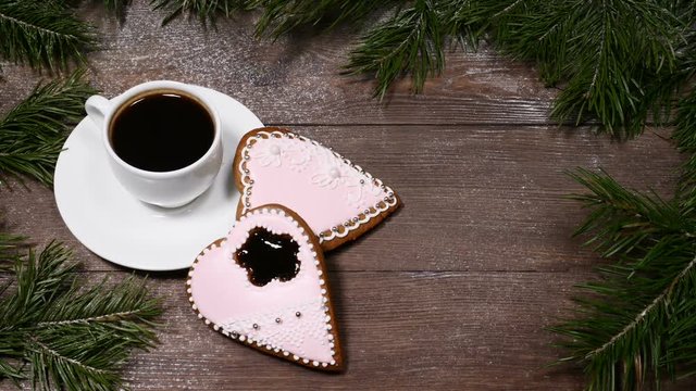 Food art. Good morning concept. Fir tree as a frame, cup of coffee and 2 heart-shaped gingersnaps are on wooden background.