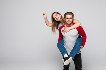 Handsome man giving piggy back to his girlfriend on white background