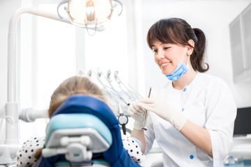 Dentist in uniform checks the oral cavity of the client in the dental office