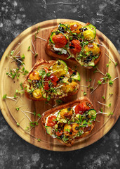 Healthy toasts with baked sweet cherry tomatoes and grilled zucchinin ribbons drizzled with balsamic vinegar