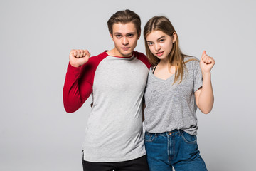 happy young couple celebrating success with hands up in the air on white background