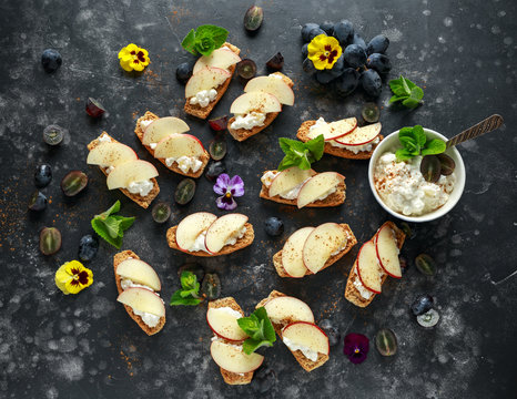 Healthy breakfast toasts with cottage cheese and nectarine slices, sprinkled with cinnamon, served with dark grapes and edible flowers - Powered by Adobe