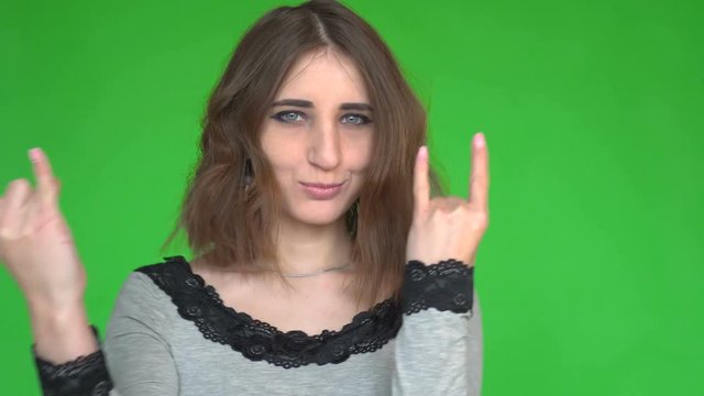 Punk is not dead. Attractive cool young woman making horn sign hand gesture over green background