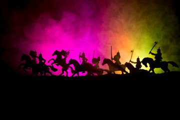 Naklejka na ściany i meble Medieval battle scene with cavalry and infantry. Silhouettes of figures as separate objects, fight between warriors on dark toned foggy background. Night scene.