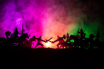 Fototapeta premium Medieval battle scene with cavalry and infantry. Silhouettes of figures as separate objects, fight between warriors on dark toned foggy background. Night scene.