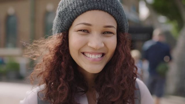 close up portrait of pretty mixed race girl smiling happy at camera wearing beanie hat