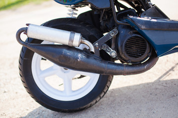 Obraz premium Rear wheel with exhaust of blue modern scooter on the gravel road