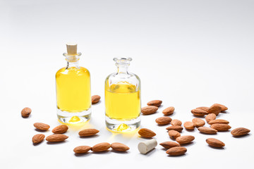 Bottles of almond oil and almonds  on white background, copyspace.
