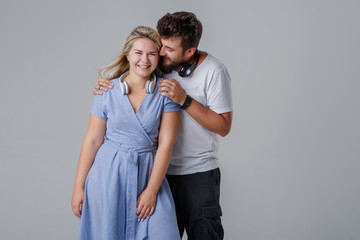 Fototapeta premium Young cheerful and cheerful couple with wireless headphones, smiling against a gray background. Club DJs