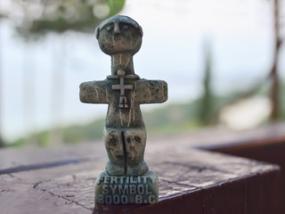 Idol of Pomos, ancient symbol of fertility on Cyprus. A small sculpture on a blurred background. Traditional souvenir for tourists.