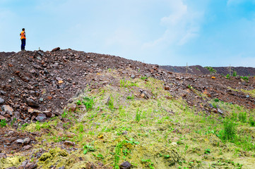 The worker is at the top of the rock heap in his quarry