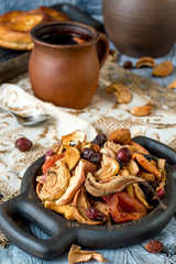 A mixture of dried fruits for compote on a round wooden plate on an old table.  