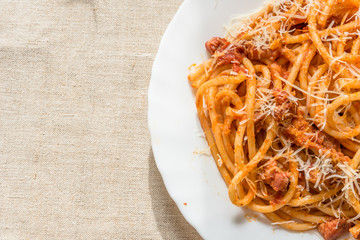 Classical Italian Pasta Amatriciana in a white plate close-up, copy space for a recipe