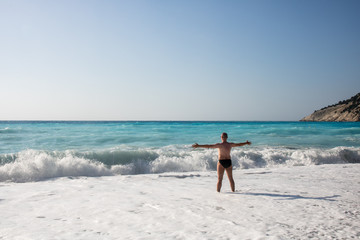 Man chasing the waves on Myrtos beach, island Kefalonia, Greece
