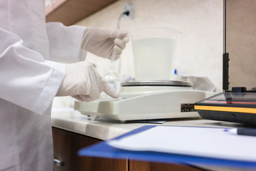 Side view close-up of the hands of an expert in chemical substances, analyzing liquid sample with modern equipment in the laboratory of a cosmetics factory