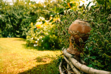 Old clay jug and green summer garden