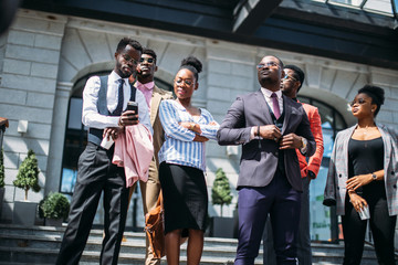 low angle view. cute woman is looking at the phone of her colleague while other employees are...