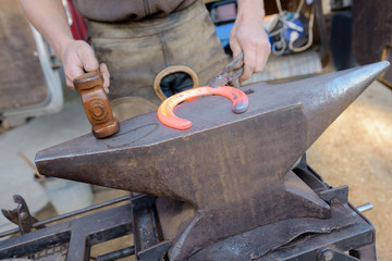 a blacksmith forging a horse shoe on an anvil