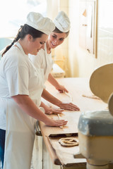 Baker women working in bakehouse of bakery looking into camera