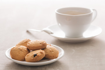 Coffee. White porcelain cup of freshly brewed coffee top view close-up arranged with  biscuits, spoon and plate on light background