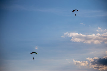 Shapes of paragliders against the background of a slightly cloudy sky
