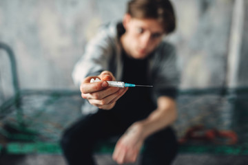 Male junkie reaching out hand with syringe