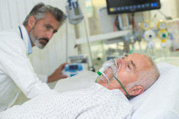 Obraz na płótnie Canvas doctor monitoring patient wearing oxygen mask