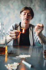 Drug addict with spoon and matches prepares a dose