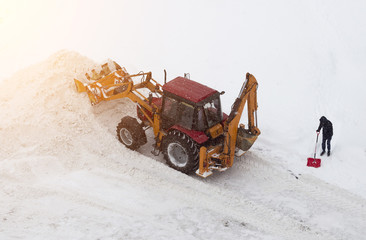 Red tractor and man with a shovel on snow cleaning