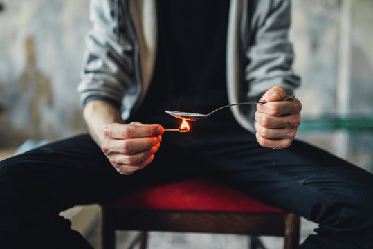 Junkie hands with spoon and matches prepares dose