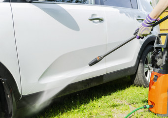Fototapeta premium Manual car wash with pressurized water in car wash outside. Summer Car Washing. Cleaning car using high pressure water. Car detailing. Hand washer.