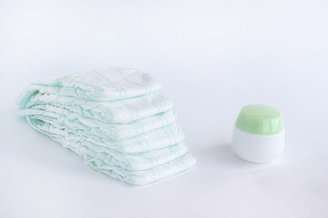 Fototapeta na wymiar Baby diapers on a white background and a jar with baby cream