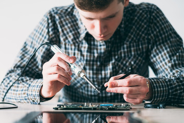 microelectronics. computer renovation in repair shop. engineer soldering motherboard