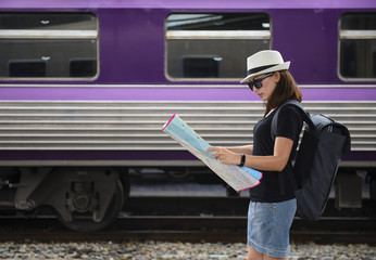 Fototapeta na wymiar Asian backpack traveler woman using generic local map at a train station