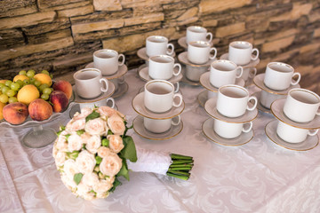 View of the served for decorated table with tea set cups and wedding bouquet