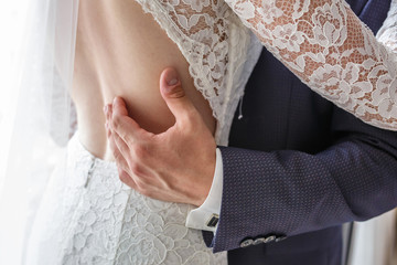 groom embraces the bride. the hands of the newlyweds. dress with open back