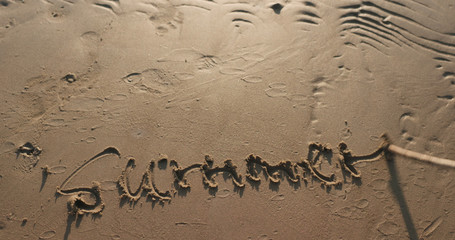 writing word summer on sand beach