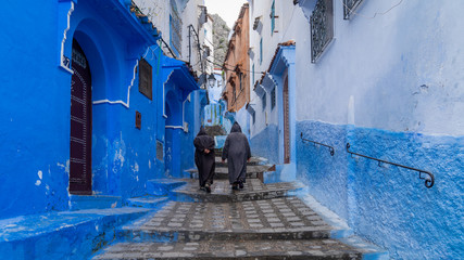 Unidentified men walking in blue medina of Chefchaouen city in Morocco, North Africa