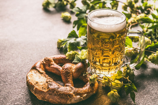 Mug of beer and pretzel with vine and cones of hops. German and Bavarian style